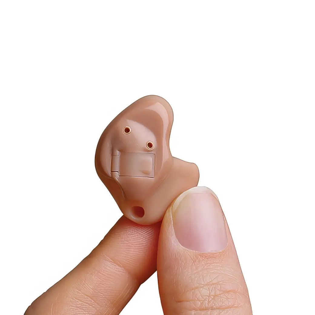 A person holding a small, beige hearing aid.