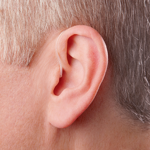 Close-up of a human ear with a hearing aid partially visible.